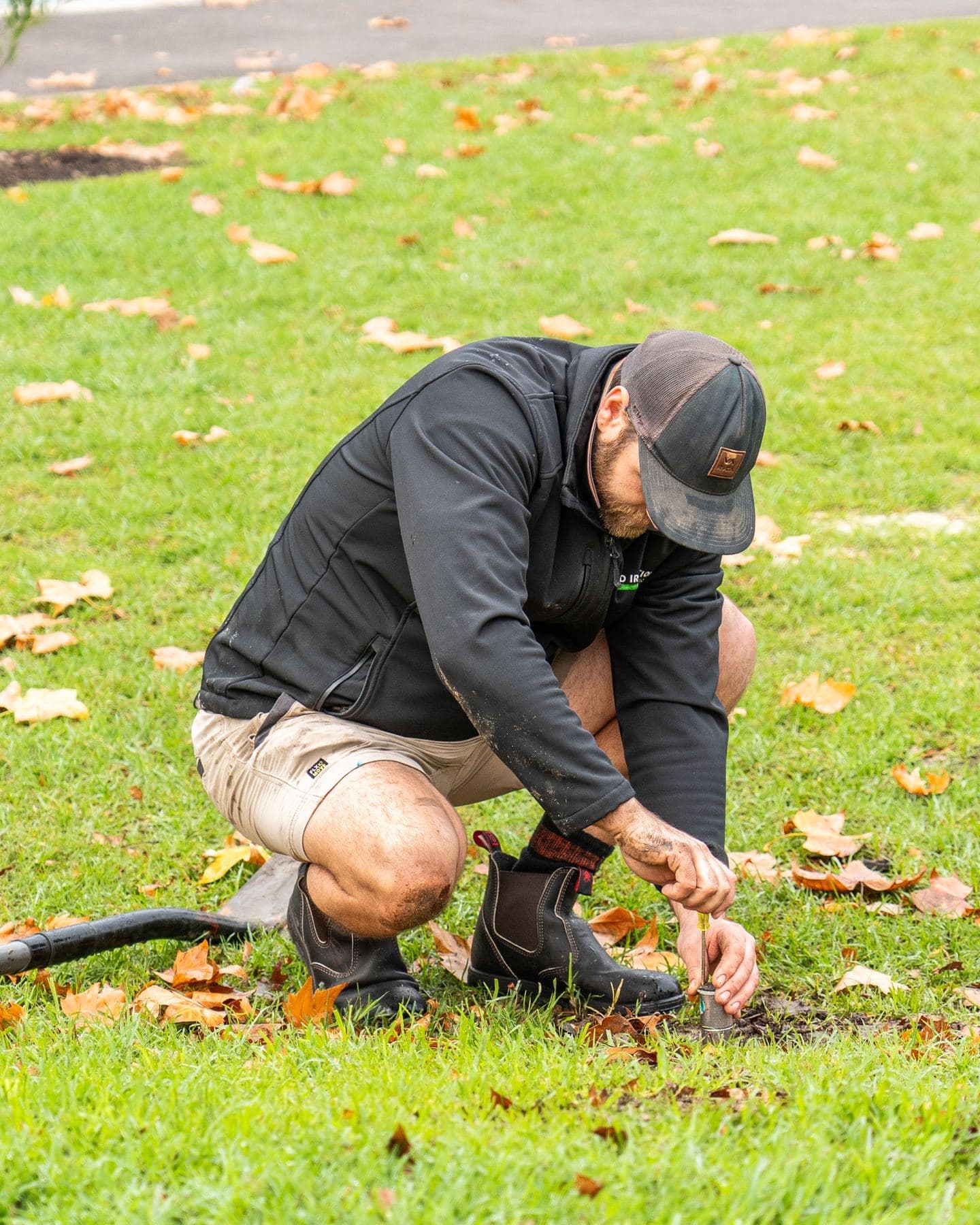 Technician servicing a sprinkler valve in a park setting