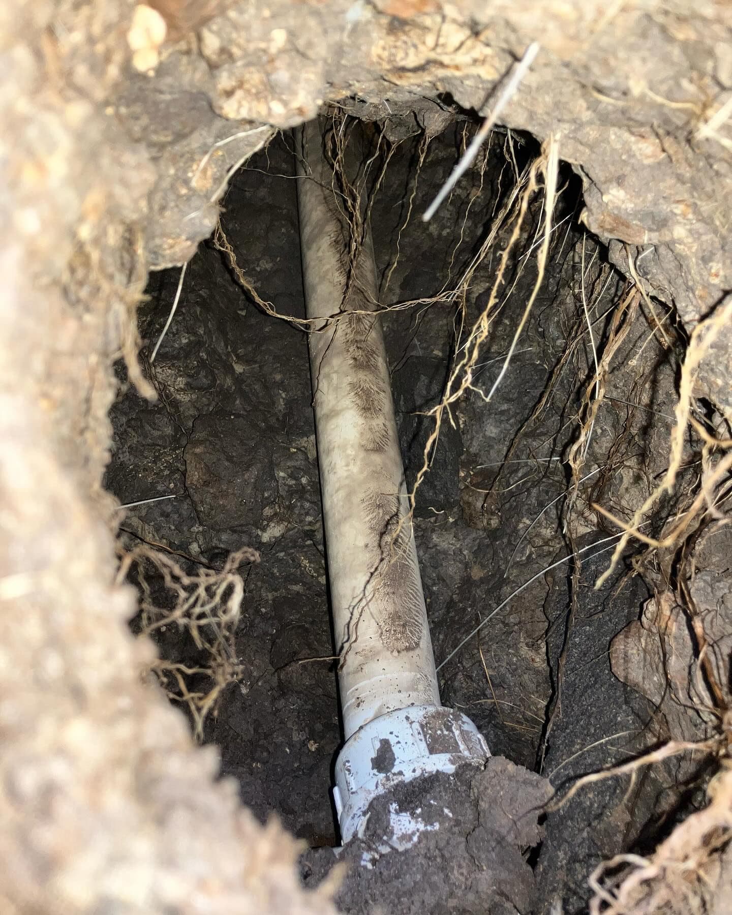 Close inspection of an irrigation pipe accessed through a bored section of ground